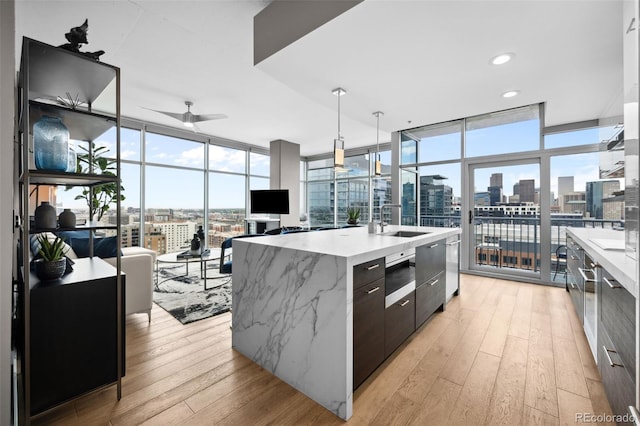 kitchen with a spacious island, hanging light fixtures, expansive windows, a sink, and modern cabinets