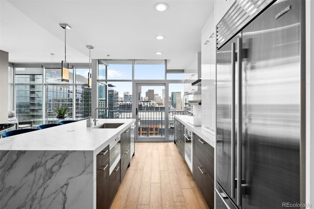 kitchen with a city view, white cabinetry, high quality fridge, a sink, and modern cabinets