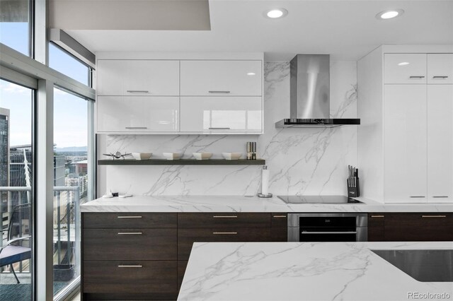 kitchen featuring wall chimney exhaust hood, modern cabinets, open shelves, and oven