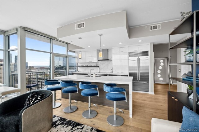 kitchen featuring built in fridge, a city view, visible vents, hanging light fixtures, and white cabinets