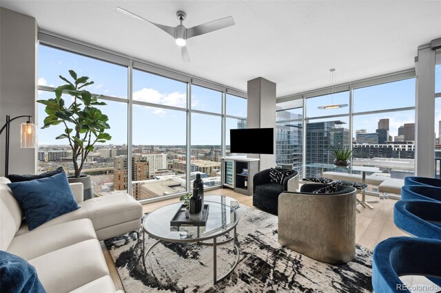 living room with a wall of windows, light wood-style flooring, and a ceiling fan