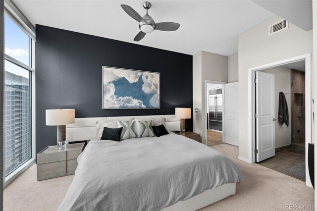 bedroom with ceiling fan, light colored carpet, an accent wall, visible vents, and baseboards