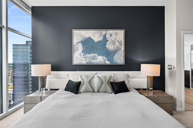 bedroom featuring a wall of windows, baseboards, a city view, and carpet flooring