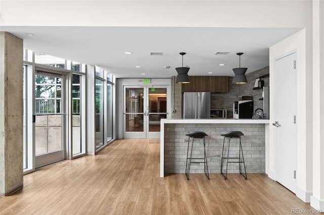 kitchen featuring a breakfast bar area, high end fridge, dark brown cabinets, fridge, and modern cabinets