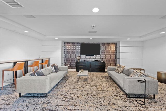 living area with recessed lighting, a raised ceiling, and visible vents