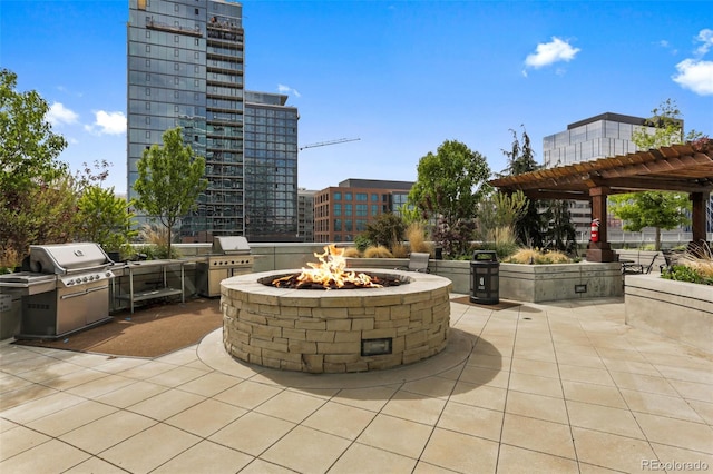 view of patio / terrace featuring a fire pit, area for grilling, exterior kitchen, a city view, and a pergola