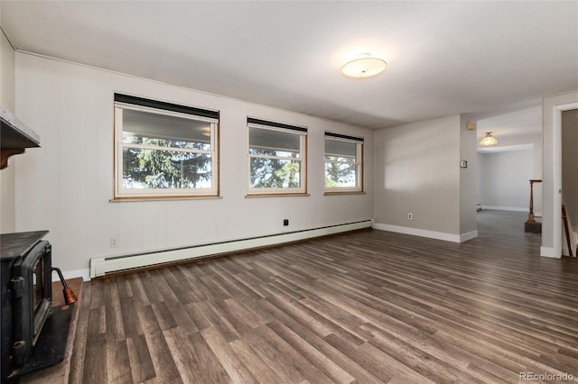 unfurnished living room with a wood stove, a baseboard heating unit, and dark hardwood / wood-style flooring