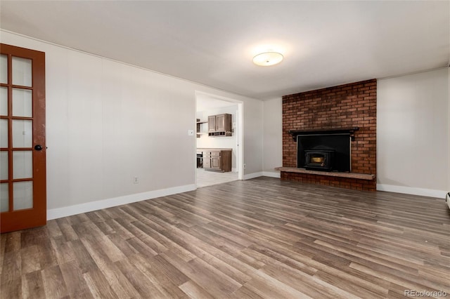 unfurnished living room with wood-type flooring and a wood stove