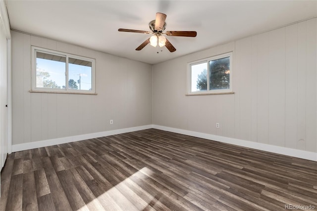 unfurnished room featuring wood walls, dark wood-type flooring, and ceiling fan