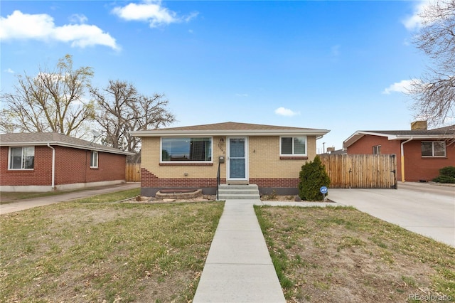 bungalow-style home with a front lawn, entry steps, fence, and brick siding