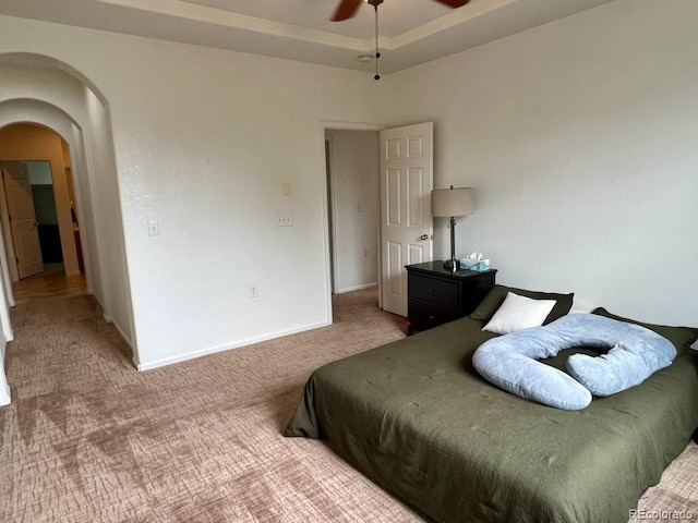 bedroom with ceiling fan, carpet flooring, and a tray ceiling