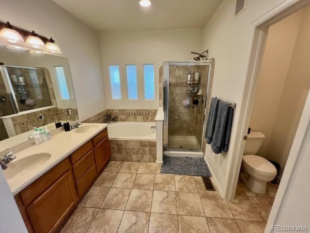 full bathroom with double sink vanity, tile patterned flooring, independent shower and bath, and toilet