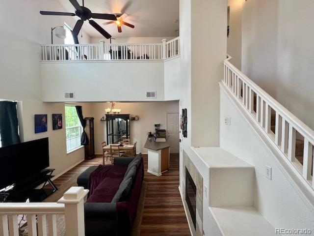 living room featuring dark hardwood / wood-style floors, a high ceiling, and ceiling fan with notable chandelier