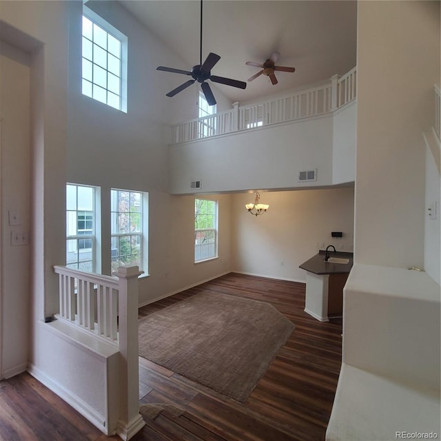 8802 E 24th Pl Unit 101, Denver, CO 80238 - unfurnished living room with dark wood-style flooring, a ceiling fan, a chandelier, a sink, and a high ceiling