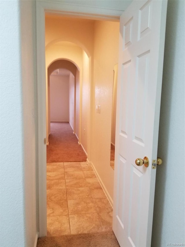 8802 E 24th Pl Unit 101, Denver, CO 80238 - hallway featuring arched walkways, light carpet, and light tile patterned floors