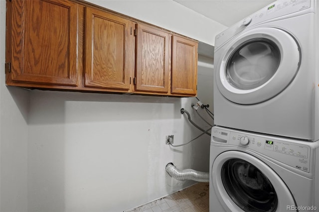 laundry area featuring stacked washer / drying machine and cabinets