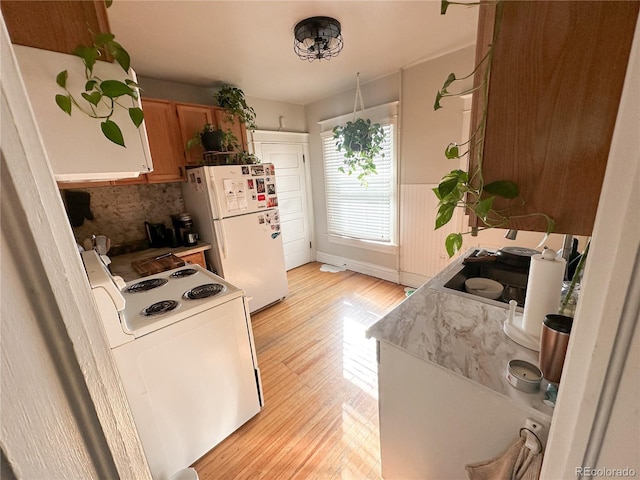 kitchen with tasteful backsplash, light hardwood / wood-style flooring, and white appliances