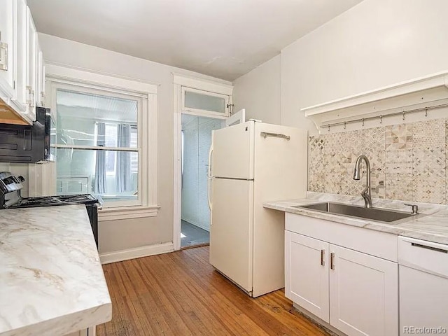 kitchen featuring sink, light hardwood / wood-style flooring, backsplash, white cabinets, and black appliances