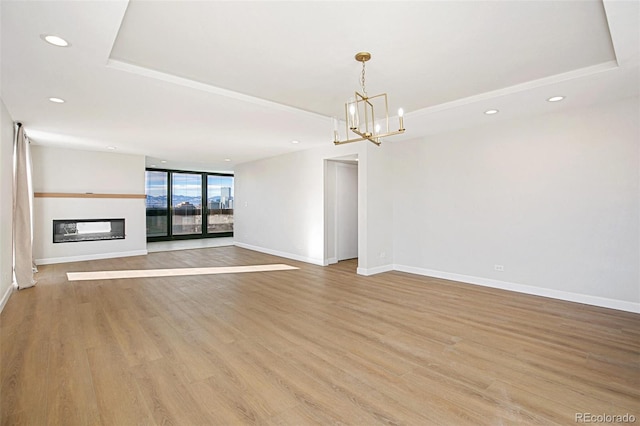 unfurnished living room featuring a chandelier, light wood-type flooring, and expansive windows