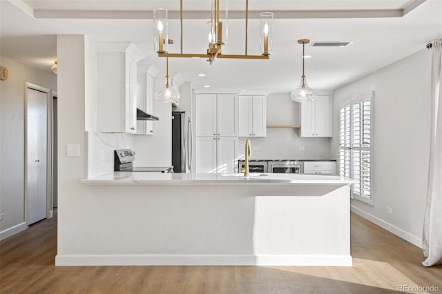 kitchen featuring electric range, backsplash, white cabinets, and hanging light fixtures