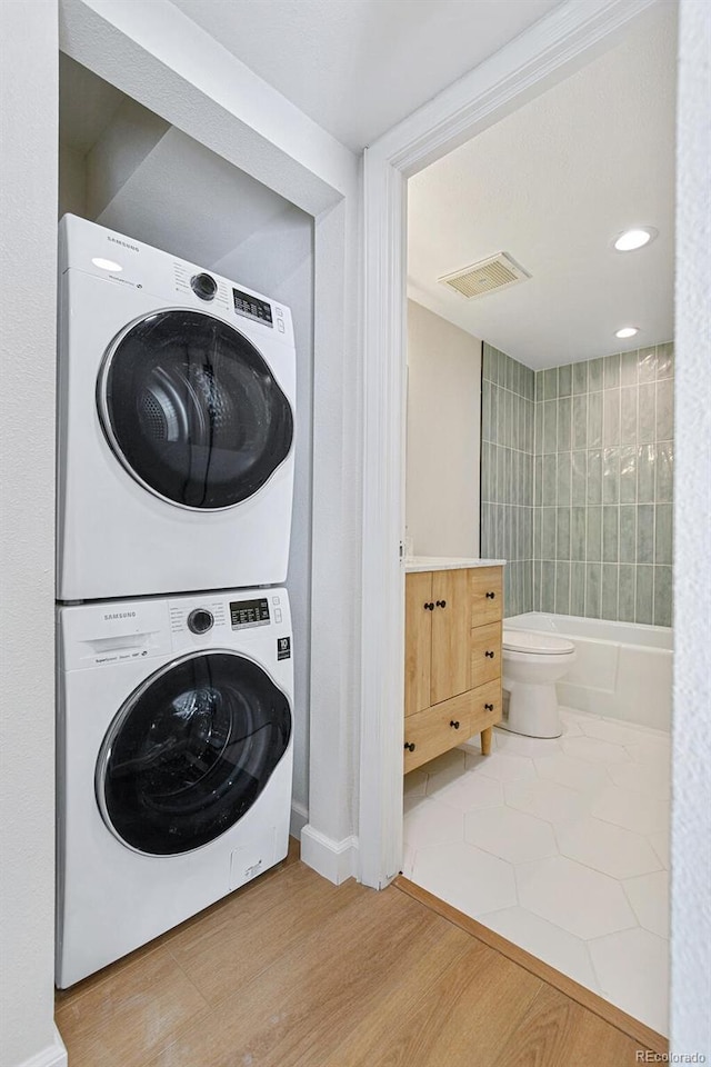 laundry room featuring stacked washer and dryer and hardwood / wood-style floors