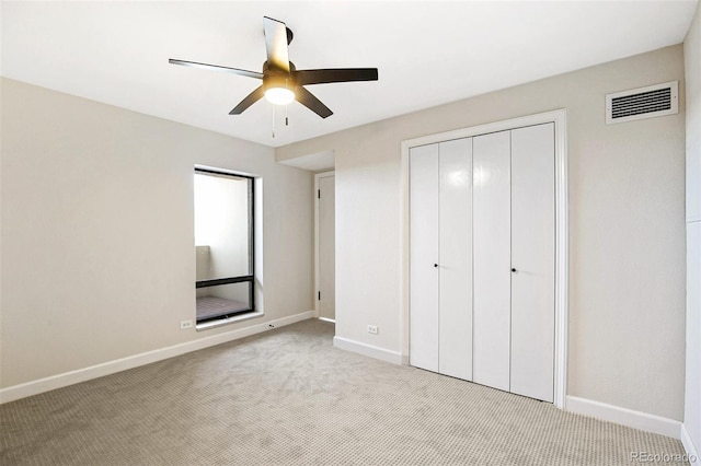 unfurnished bedroom with a closet, light colored carpet, and ceiling fan