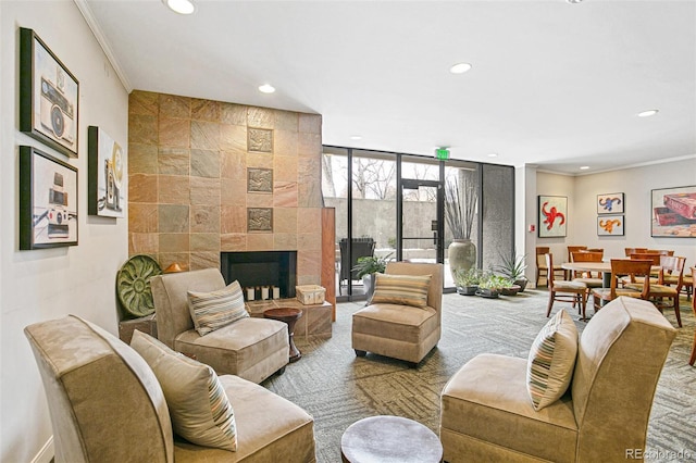 living room with a fireplace, carpet, ornamental molding, and a wall of windows