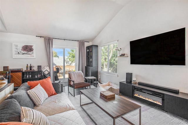 living room with light hardwood / wood-style flooring, a wealth of natural light, and high vaulted ceiling