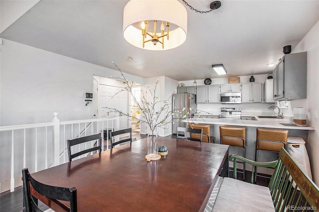 dining area with an inviting chandelier, sink, and dark hardwood / wood-style floors