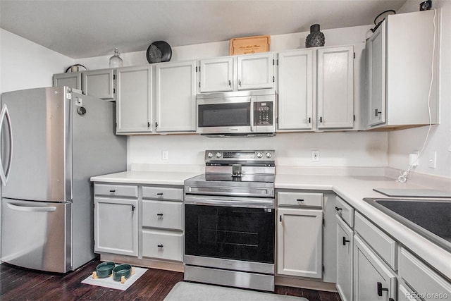 kitchen featuring appliances with stainless steel finishes, dark wood-type flooring, and white cabinets