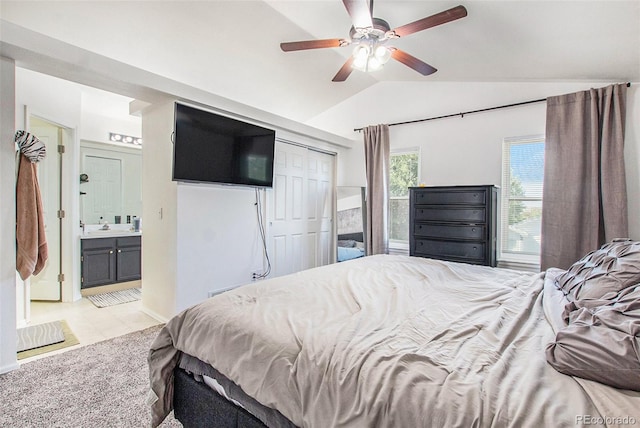 bedroom featuring a closet, lofted ceiling, light carpet, ensuite bathroom, and ceiling fan