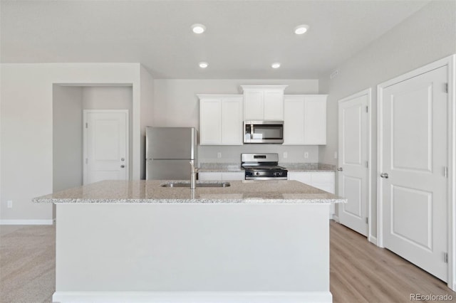 7307 Dolores Ave, Frederick, CO 80530 - kitchen featuring stainless steel appliances, a center island with sink, white cabinets, light stone countertops, and recessed lighting