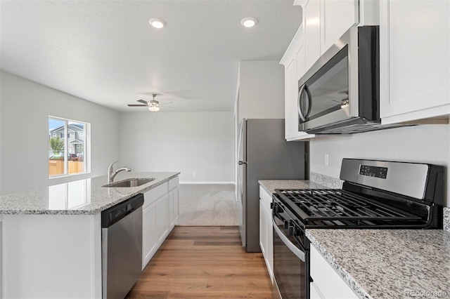 7307 Dolores Ave, Frederick, CO 80530 - kitchen with stainless steel appliances, a kitchen island with sink, white cabinetry, a ceiling fan, and light stone countertops