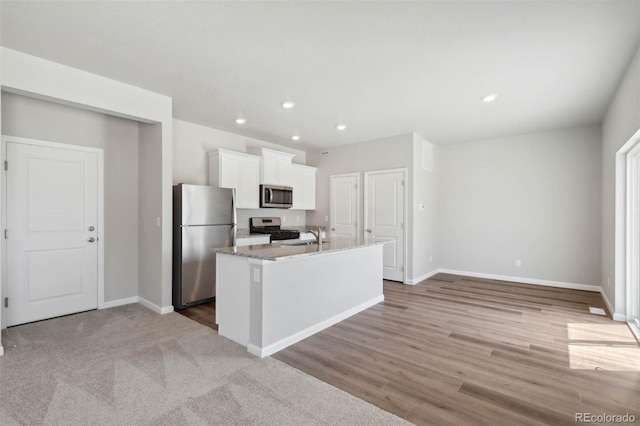 7307 Dolores Ave, Frederick, CO 80530 - kitchen featuring appliances with stainless steel finishes, white cabinetry, a center island with sink, recessed lighting, and light wood finished floors