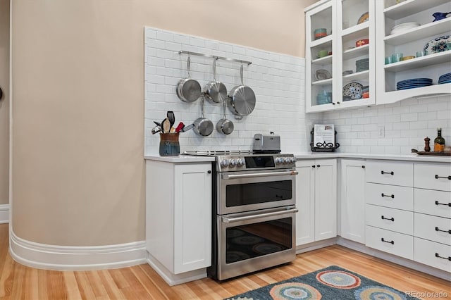 836 E 17th Ave Unit 1A, Denver, CO 80218 - kitchen with range with two ovens, light wood-type flooring, tasteful backsplash, light countertops, and white cabinetry