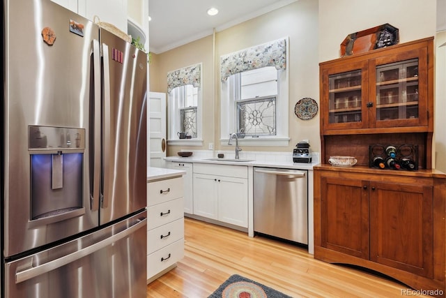 836 E 17th Ave Unit 1A, Denver, CO 80218 - kitchen with stainless steel appliances, glass insert cabinets, crown molding, light countertops, and light wood-style flooring