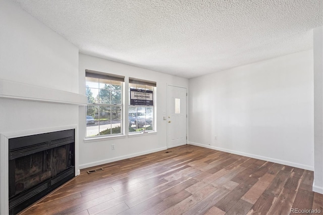 3094 W 107th Pl Unit B, Westminster, CO 80031 - unfurnished living room featuring hardwood / wood-style floors, a fireplace, and a textured ceiling