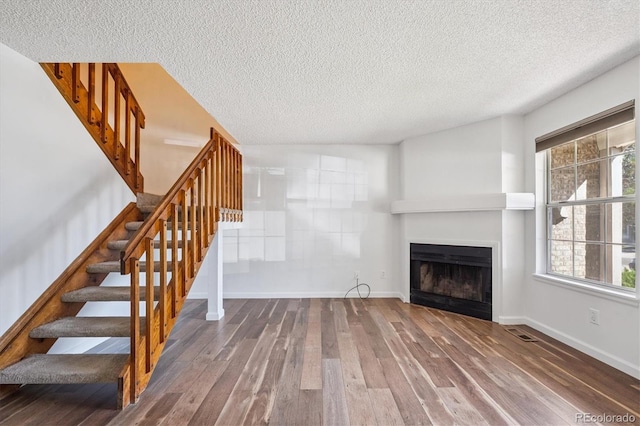 3094 W 107th Pl Unit B, Westminster, CO 80031 - unfurnished living room featuring wood finished floors, a textured ceiling, a fireplace, and stairway