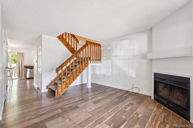 3094 W 107th Pl Unit B, Westminster, CO 80031 - unfurnished living room featuring wood finished floors, stairs, a fireplace, a textured ceiling, and vaulted ceiling