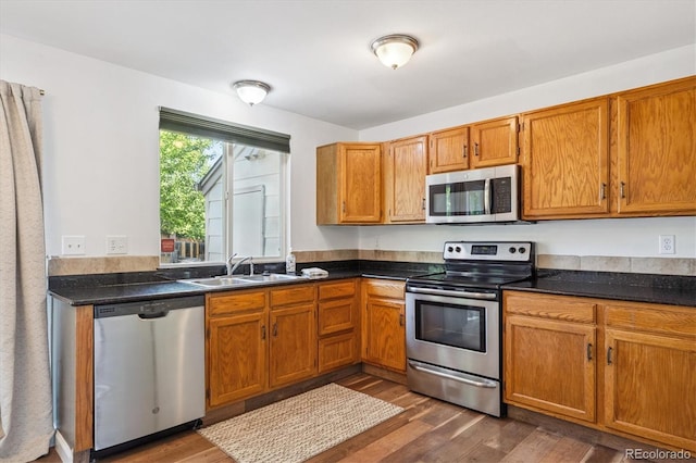 3094 W 107th Pl Unit B, Westminster, CO 80031 - kitchen with appliances with stainless steel finishes, dark wood-type flooring, brown cabinetry, and dark countertops