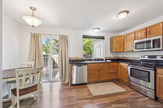 3094 W 107th Pl Unit B, Westminster, CO 80031 - kitchen with appliances with stainless steel finishes, dark countertops, dark wood-style floors, hanging light fixtures, and brown cabinets