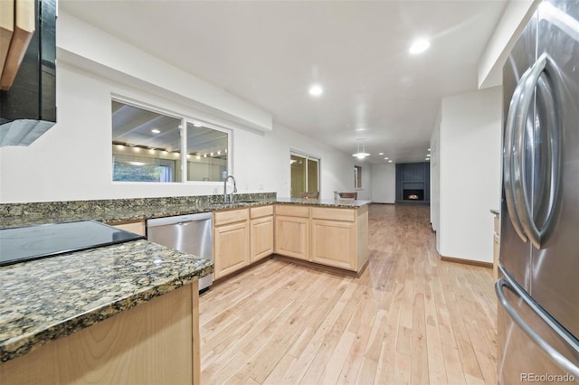 kitchen featuring light brown cabinets, dark stone counters, sink, light hardwood / wood-style floors, and stainless steel appliances