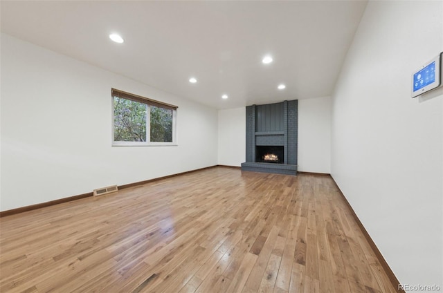 unfurnished living room featuring a brick fireplace and light hardwood / wood-style flooring