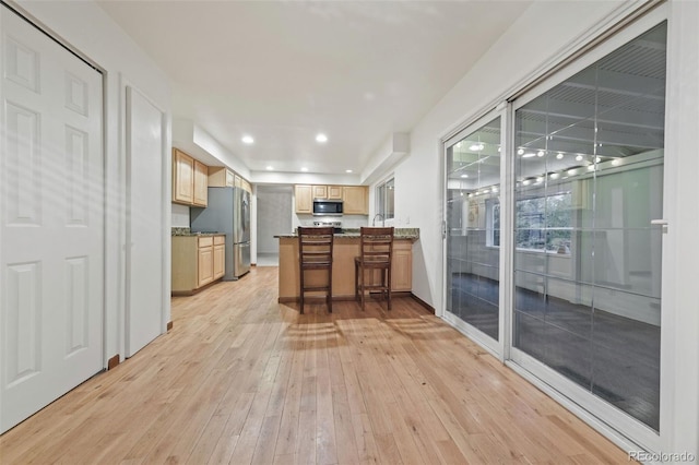 kitchen with a breakfast bar, stainless steel appliances, and light hardwood / wood-style floors