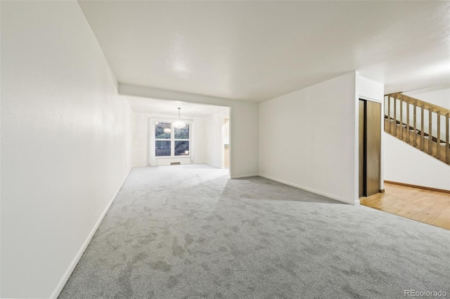 unfurnished living room with light carpet and a chandelier