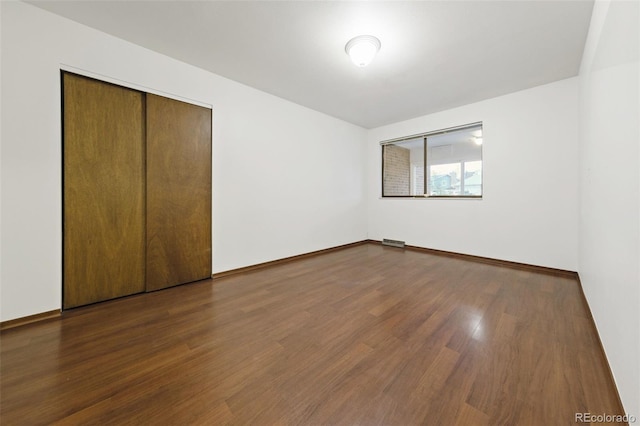 unfurnished bedroom with dark hardwood / wood-style flooring and a closet