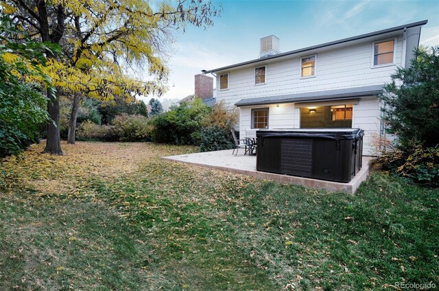 back of property with a hot tub, a patio area, and a lawn