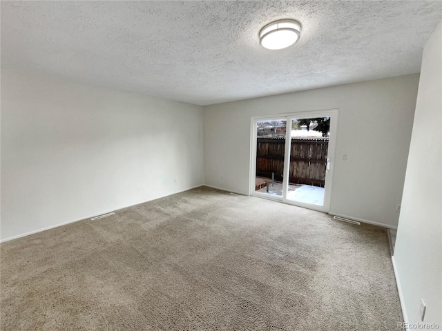 carpeted empty room featuring a textured ceiling