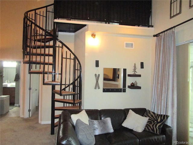 living area featuring carpet, visible vents, a high ceiling, and stairs