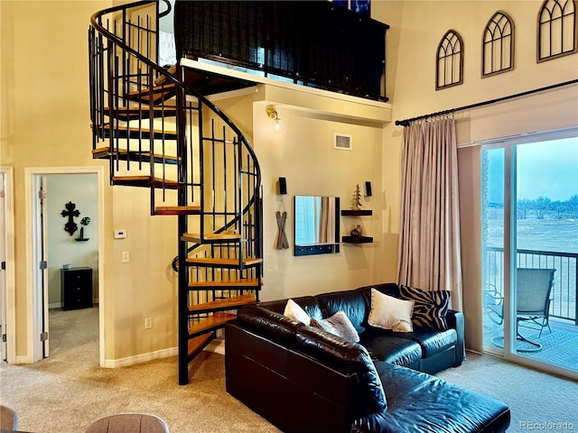 living room with carpet floors, a high ceiling, a water view, and visible vents